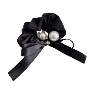 Elegant black velvet scrunchie with long ribbon bow and white pearls on white background