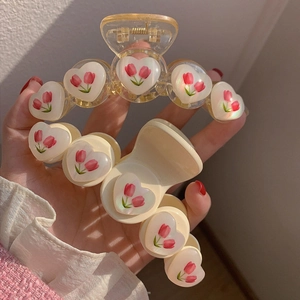 Pinze per capelli con tulipani e cuori in crema e giallo, set da due pezzi tenuto in mano