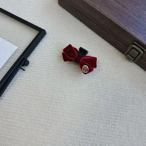 Detailed macro view of dark red velvet bow hair clip with engraved gold metal charm