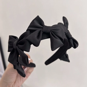 Gros plan détaillé d'un serre-tête en satin noir orné de cinq nœuds 3D élégants