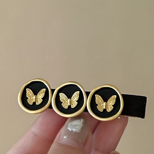 Detail of vintage black hair clip featuring gold butterfly metal charms on fabric base