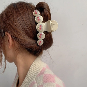 Dettaglio di una pinza per capelli con cuori e tulipani indossata su uno chignon
