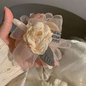 Detailaufnahme der handgefertigten beige Organza-Blüten-Haarklammer mit Webeetikett