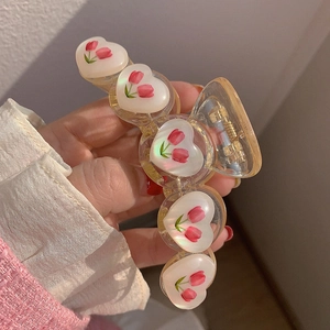 Dettaglio molletta per capelli ambra con cuori bianchi e decorazioni floreali di tulipani