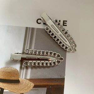 Close-up of minimalist silver metal hair clips with decorative chain edge on a fashion magazine