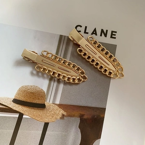 Close-up of golden metal chain hair clips with classic alligator closure on magazine