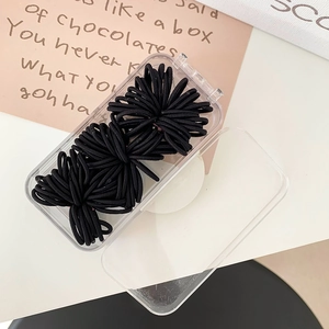 Detail of high-elastic black hair ties neatly organized in a transparent portable box