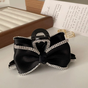 Macro detail of black satin bow hair claw clip with sparkling rhinestones edges