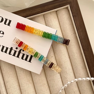 Detail of colorful rainbow rhinestone hair clips on a velvet tray with elegant gold finish