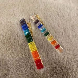 Detail of rainbow rhinestone hair clips with gold metal base on soft plush background