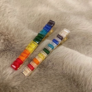 Rainbow crystal hair clips with gold alloy base on a soft plush textured background