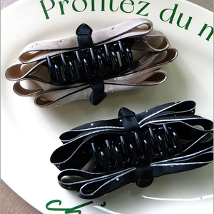 Detail of satin bow hair clips with rhinestone edges in champagne and black colors