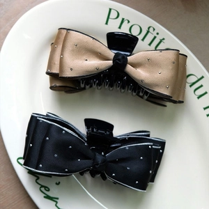 Detail of satin bow hair claws in champagne and black with sparkling rhinestones