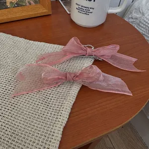 Lot de barrettes nœuds en organza rose sur fond de bois pour un style romantique