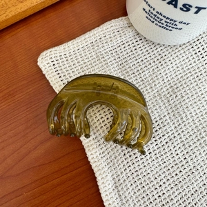 Vue détaillée d'une grande pince à cheveux en résine vert olive translucide sur tricot