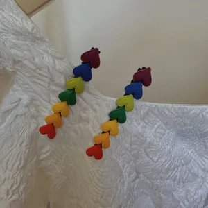 Close-up of two colorful heart-shaped hair clips with a matte finish on white fabric
