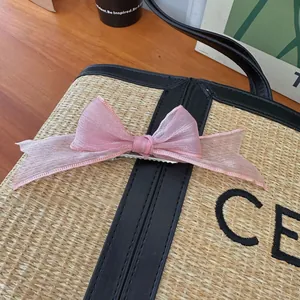 Détail de la barrette à nœud en organza rose avec tissu texturé et pince crocodile en métal