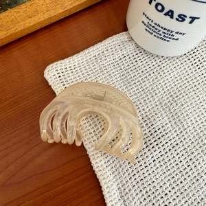 Détail d'une grande pince à cheveux ambre translucide avec design multi-dents sur tricot