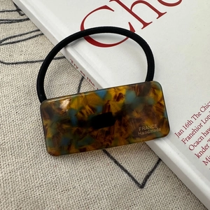 Close-up of tortoise shell resin piece with gold lettering on a high-elastic hair tie