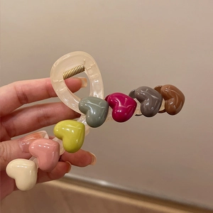 Detail showing colorful 3D hearts on a translucent hair claw clip with a gold metal spring