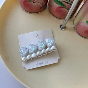 Detail of two sweet heart-shaped hair clips with pearls and colorful sequins