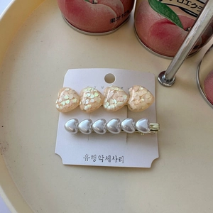 Detail view of heart-shaped sequins and pearl hair clips set on a display card