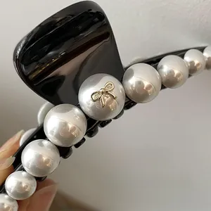 Détail macro d'une pince à cheveux en résine brillante avec perles et nœud doré élégant