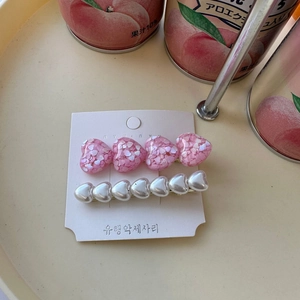 Close-up of sparkling pink sequin and white pearl heart hair clips on display card