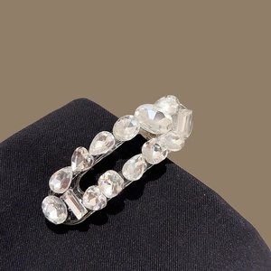 Vue macro détaillée d'une pince à cheveux géométrique en zircon avec cristaux sur tissu noir