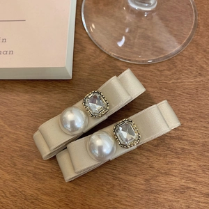 Detail of champagne satin bow hair clips with faux pearl and crystal rhinestone accents