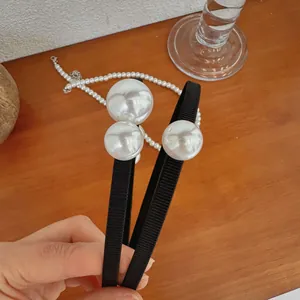 Detail showing two black fabric headbands with large white pearl accents in a lifestyle setting