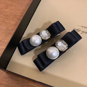 Detail of black satin ribbon hair clips with rhinestone and pearl centerpieces