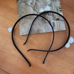 Detail view of two minimalist black fabric headbands with elegant large white pearls