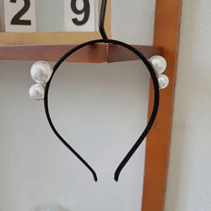 Close-up of minimalist black headband with elegant white pearls on a wooden shelf