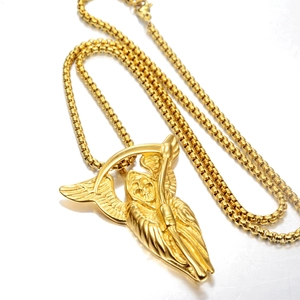 Détail du pendentif tête de mort faucheuse dorée avec ailes et faux sur chaîne maille