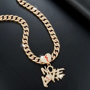 Macro-opname van gouden cubaanse ketting met NO LOVE harthanger en kristallen