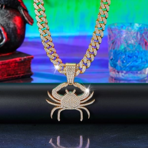 Macro detail of gold crab pendant with green gem eyes on iced out cuban link chain