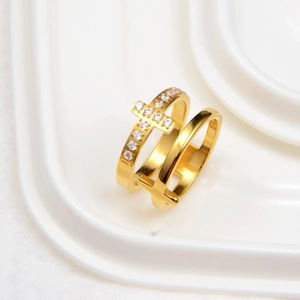 Détail d'une bague double dorée avec une croix polie et une autre sertie de cristaux