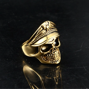 Macro shot of vintage gold skull officer ring with eagle emblem on a dark reflective surface