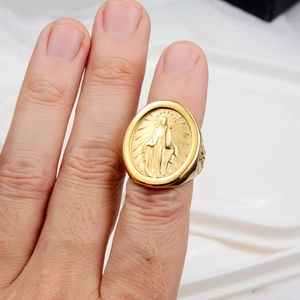 Vue détaillée d'une bague ovale dorée vintage avec relief religieux sur la main