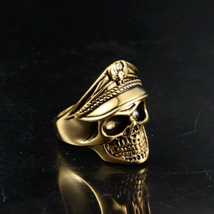 Detail of a golden gothic skull ring featuring an officer military cap on black surface