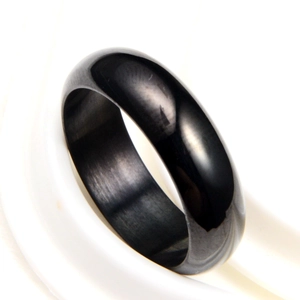Macro detail of a minimalist polished black ceramic ring with a sleek mirror finish surface