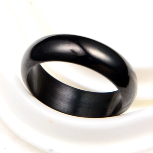 Polished black minimalist circular ring with a smooth finish on a white display stand