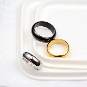Close-up of three polished minimalist rings in black, gold, and silver finishes