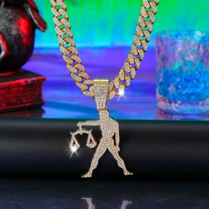 Macro view of gold-plated iced out Cuban chain with Libra zodiac sign pendant