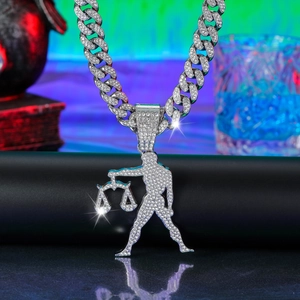 Close-up of iced out silver Cuban link chain with a diamond Libra zodiac pendant