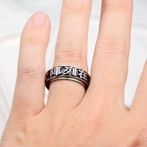 Détail d'une bague large en acier inoxydable avec gravure de mantra et finition antique