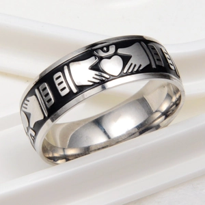 Détail macro d'une bague Claddagh avec mains tenant un cœur couronné et émail noir