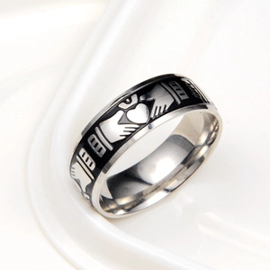 Détail macro de bague Claddagh avec mains en émail noir tenant cœur et couronne