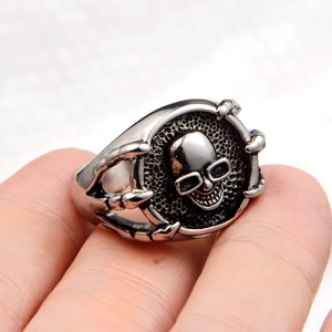 Detail of retro punk skull ring featuring hawk claw setting and oxidized steel finish